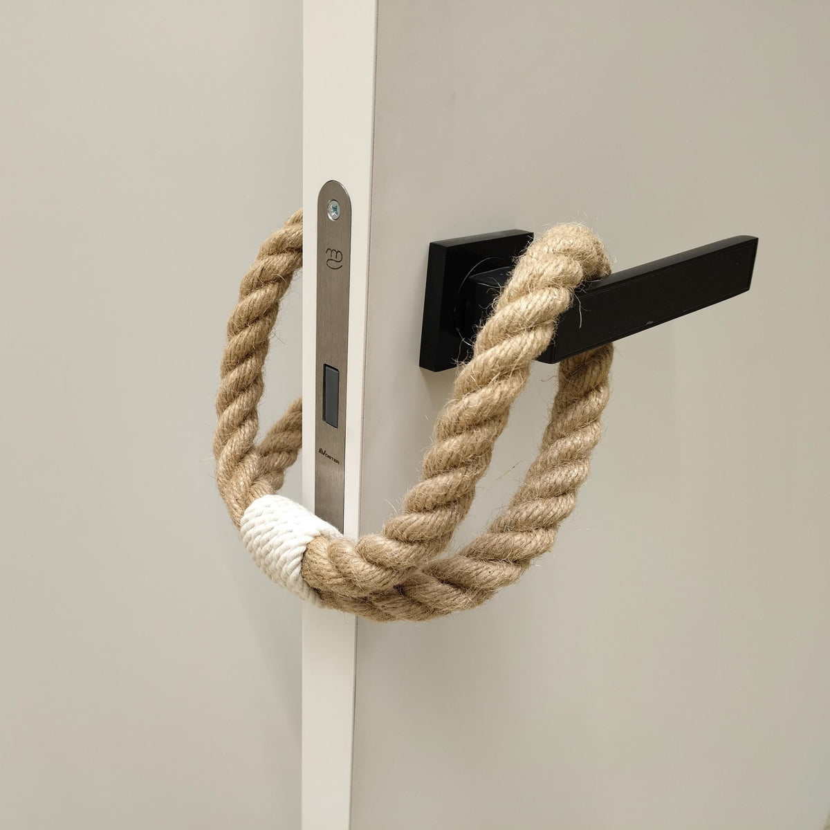 Nautical-style rope handle on a door with a black metal bracket.