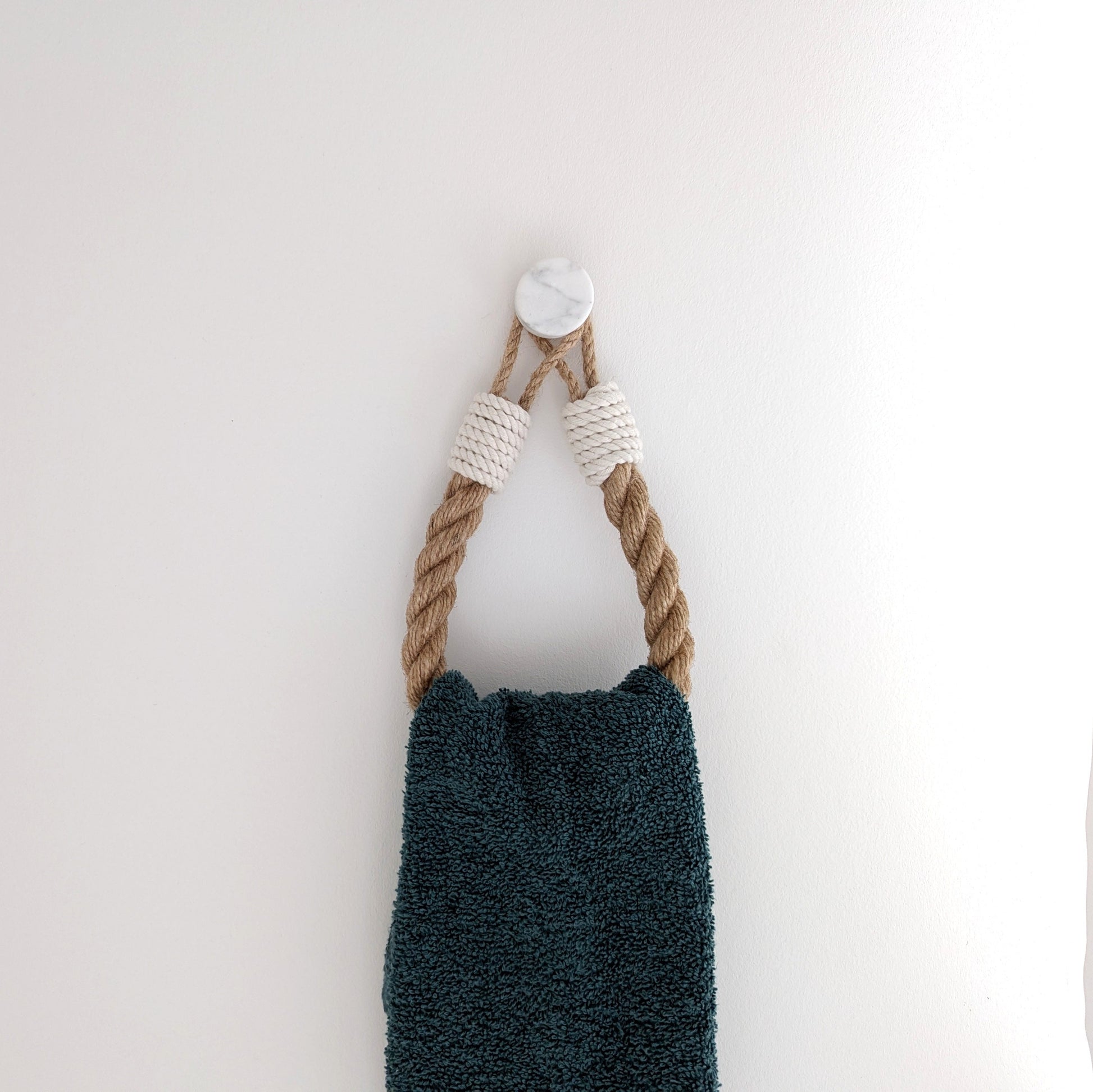 Blue towel hanging on a rope against a white wall