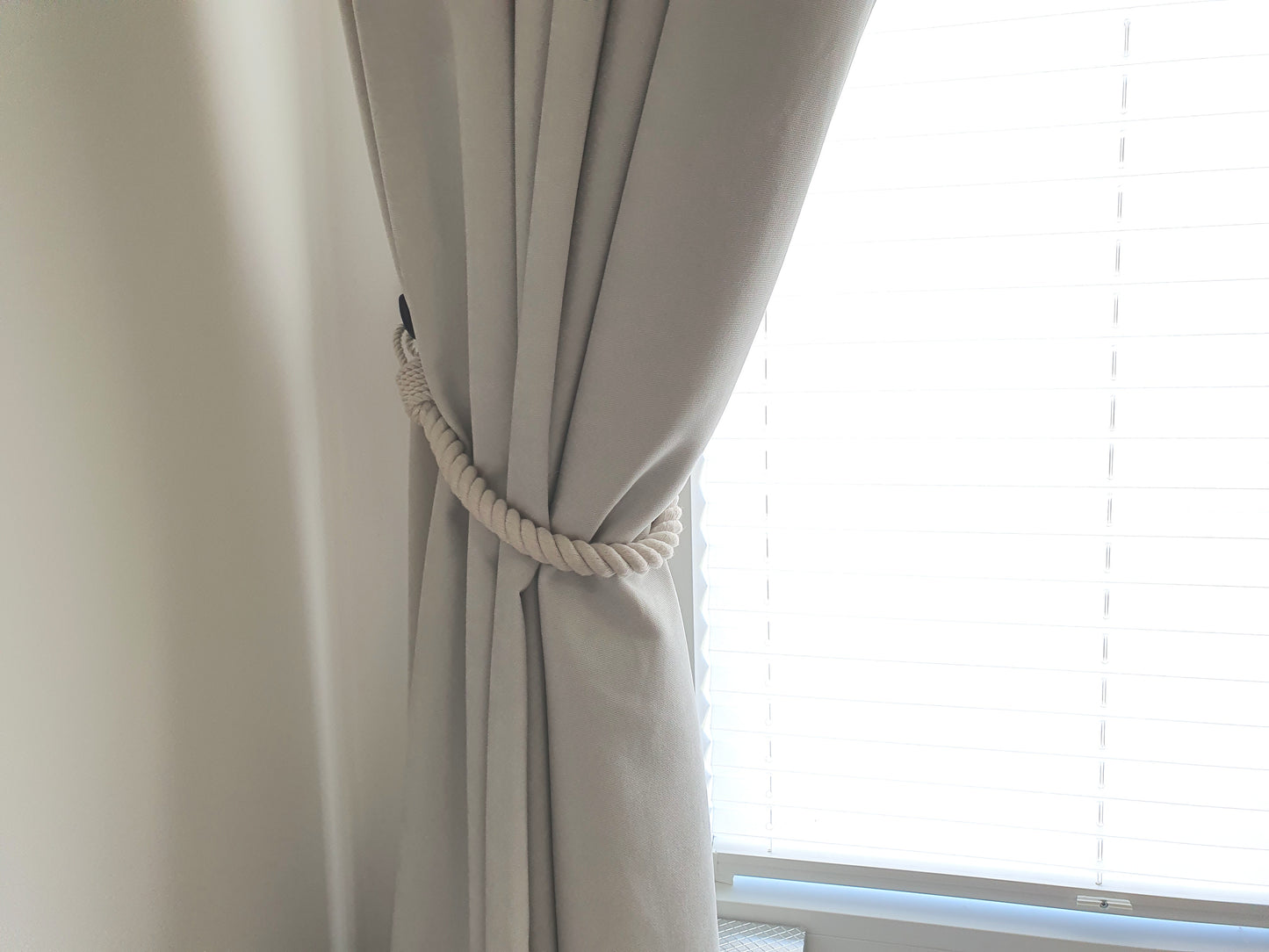 Beige curtain with a tieback in front of a window