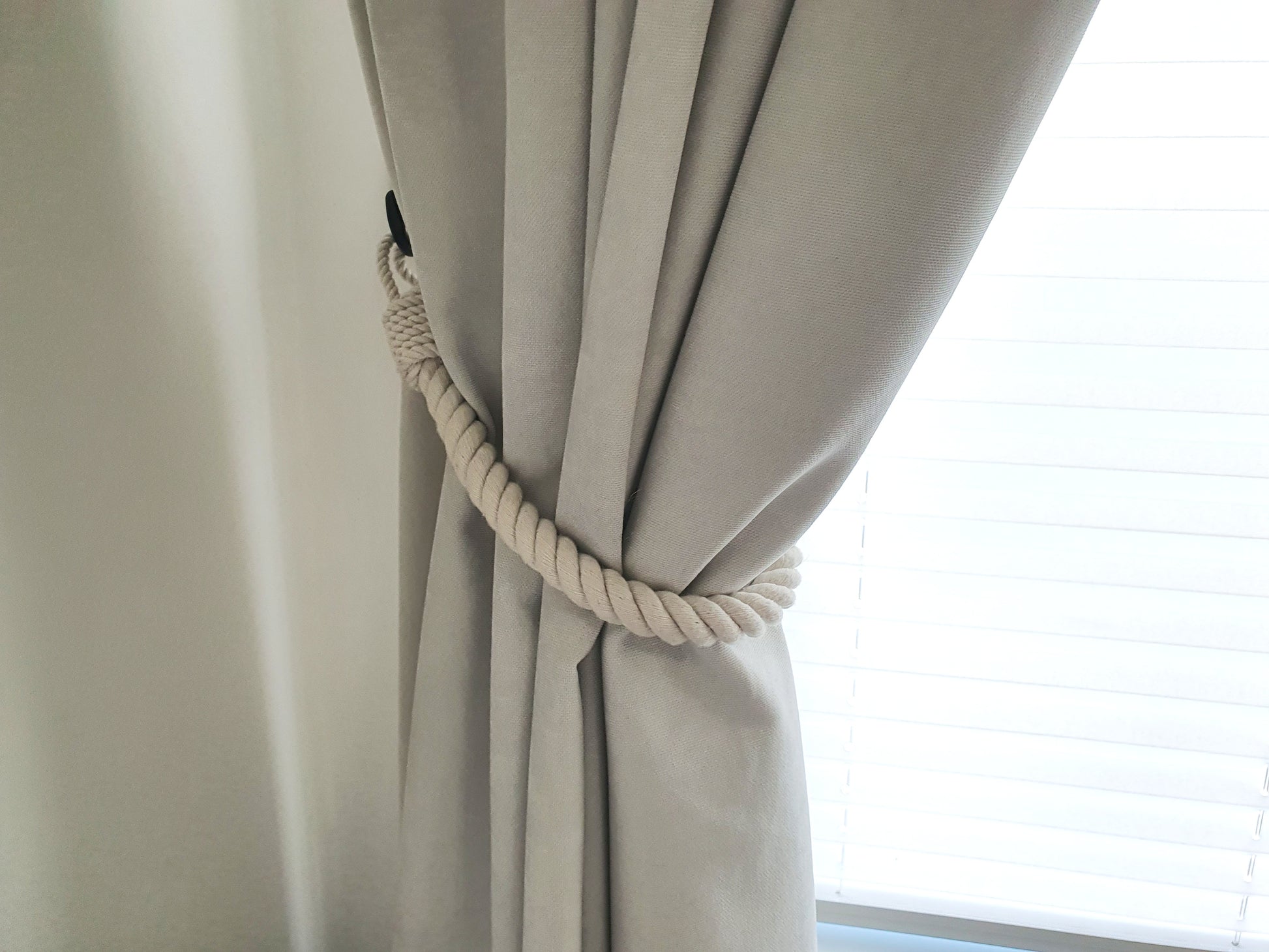 White curtain with a rope tieback in front of a window