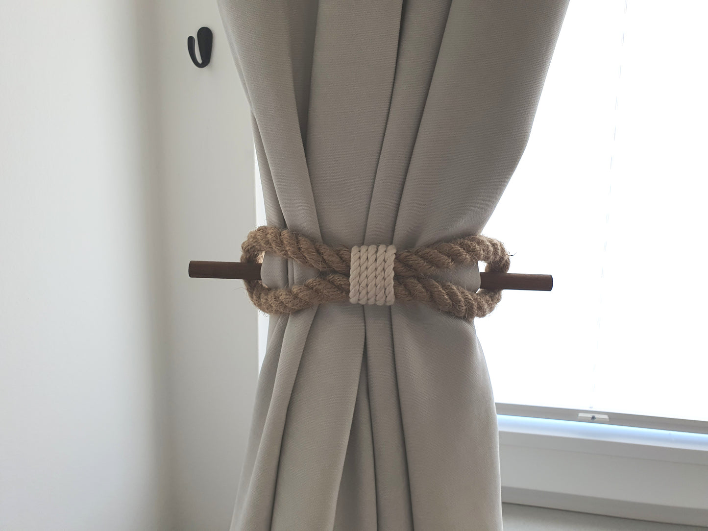 Curtain tied with a decorative rope tieback in a neutral setting
