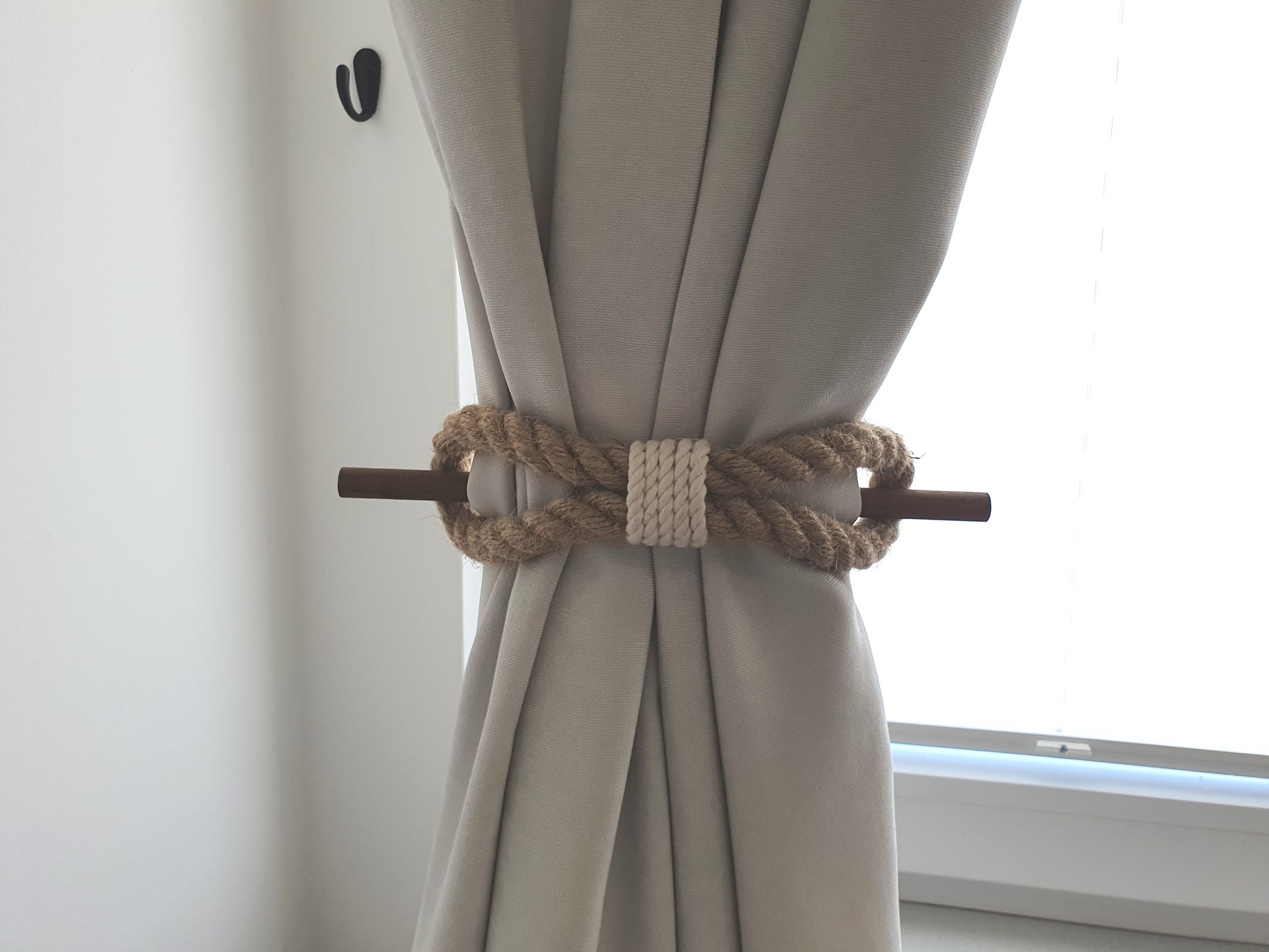 Curtain tied with a decorative rope tieback in a neutral setting