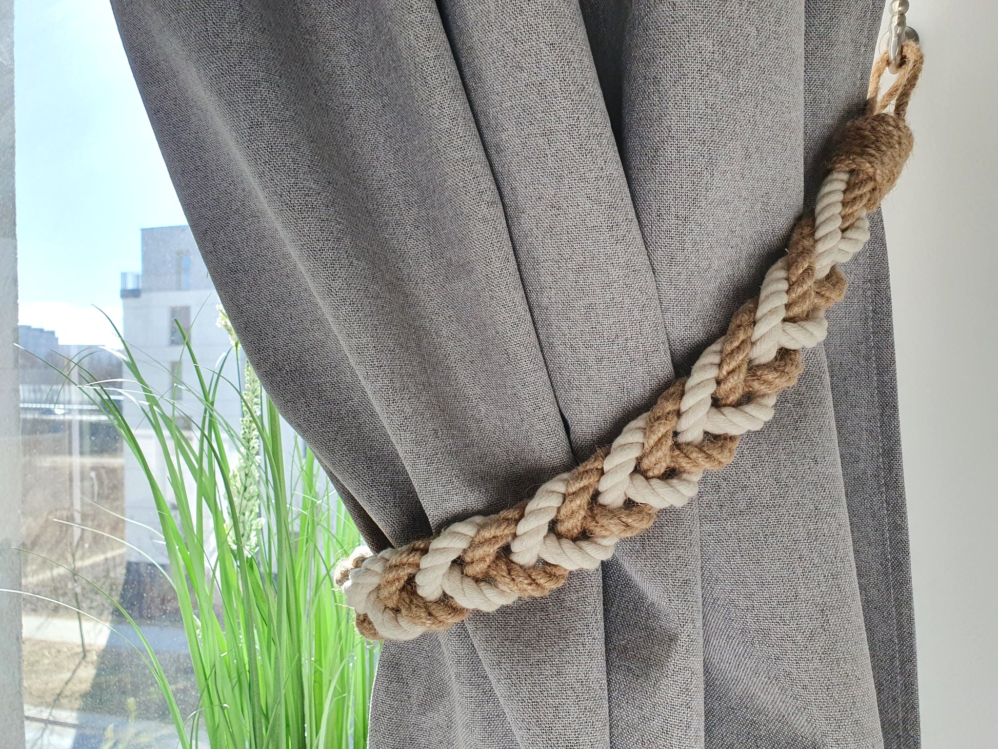 Gray curtain with a braided beige and brown curtain tieback