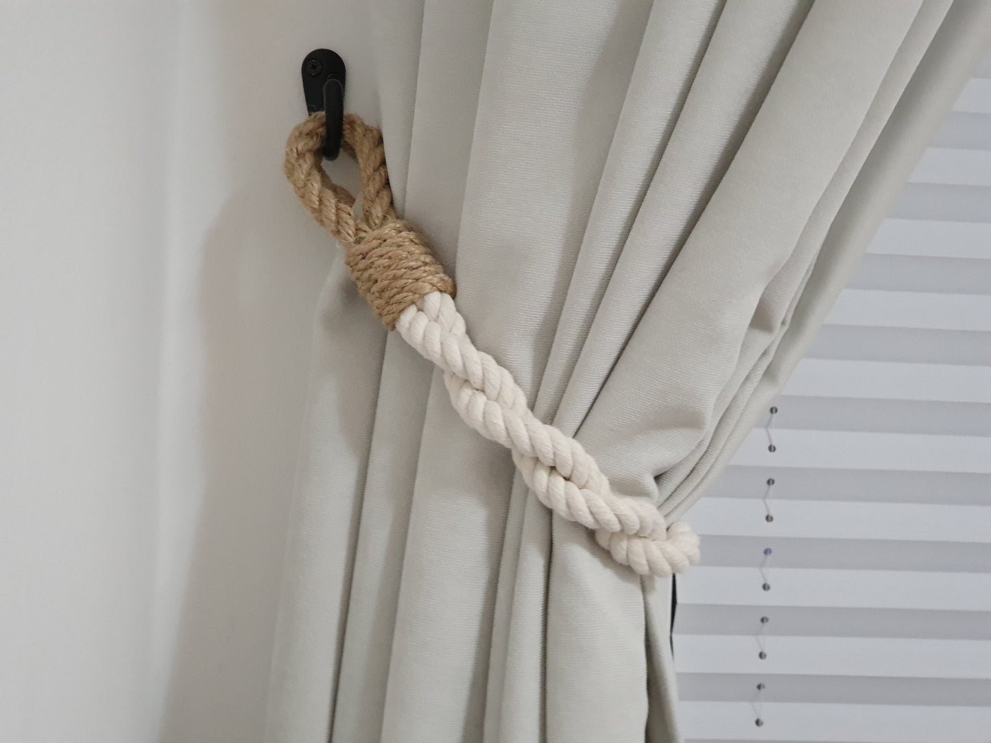 Curtain tieback with rope and metal clip on a beige curtain