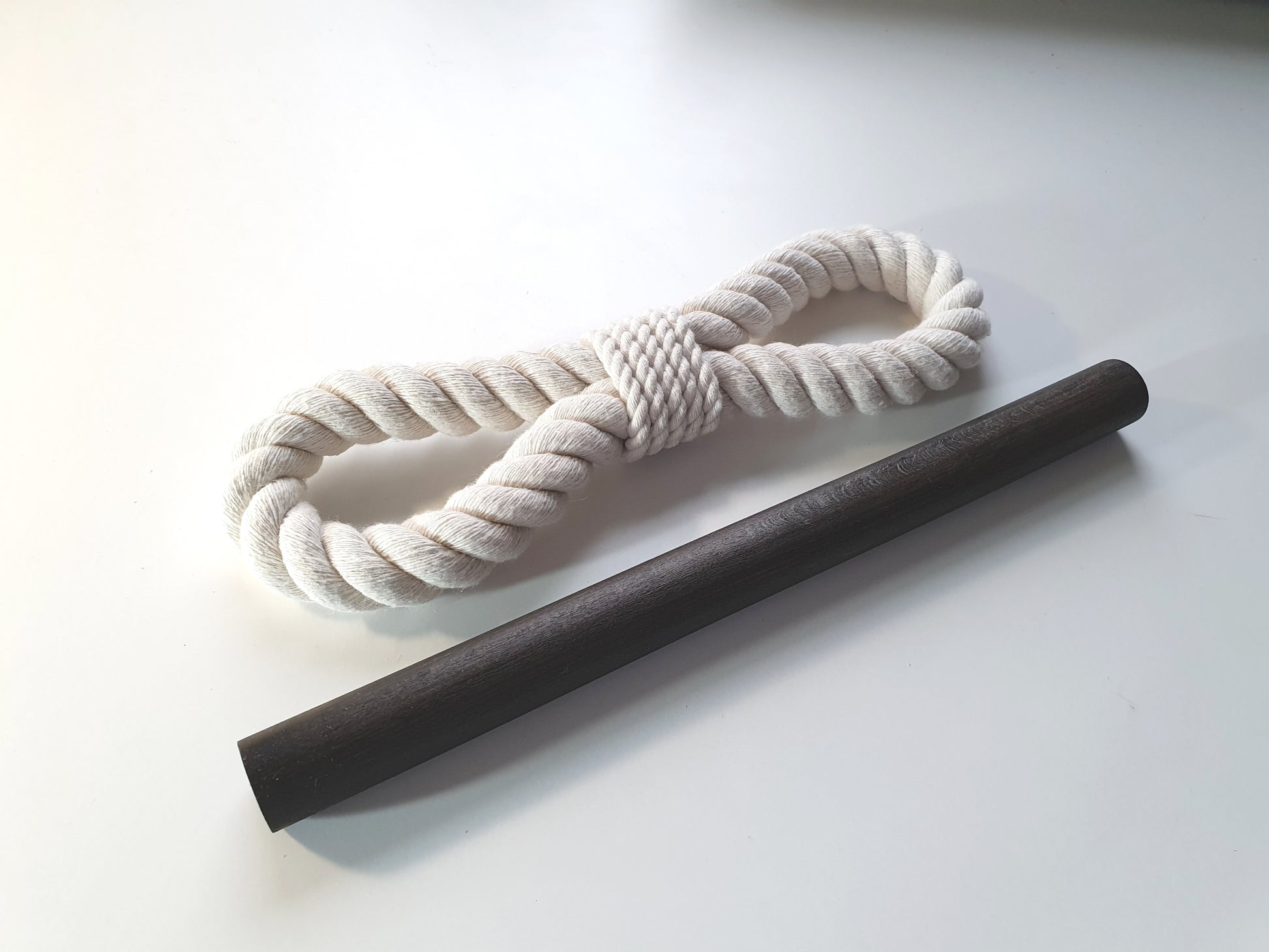 White rope and black stick on a white backgroun, tieback