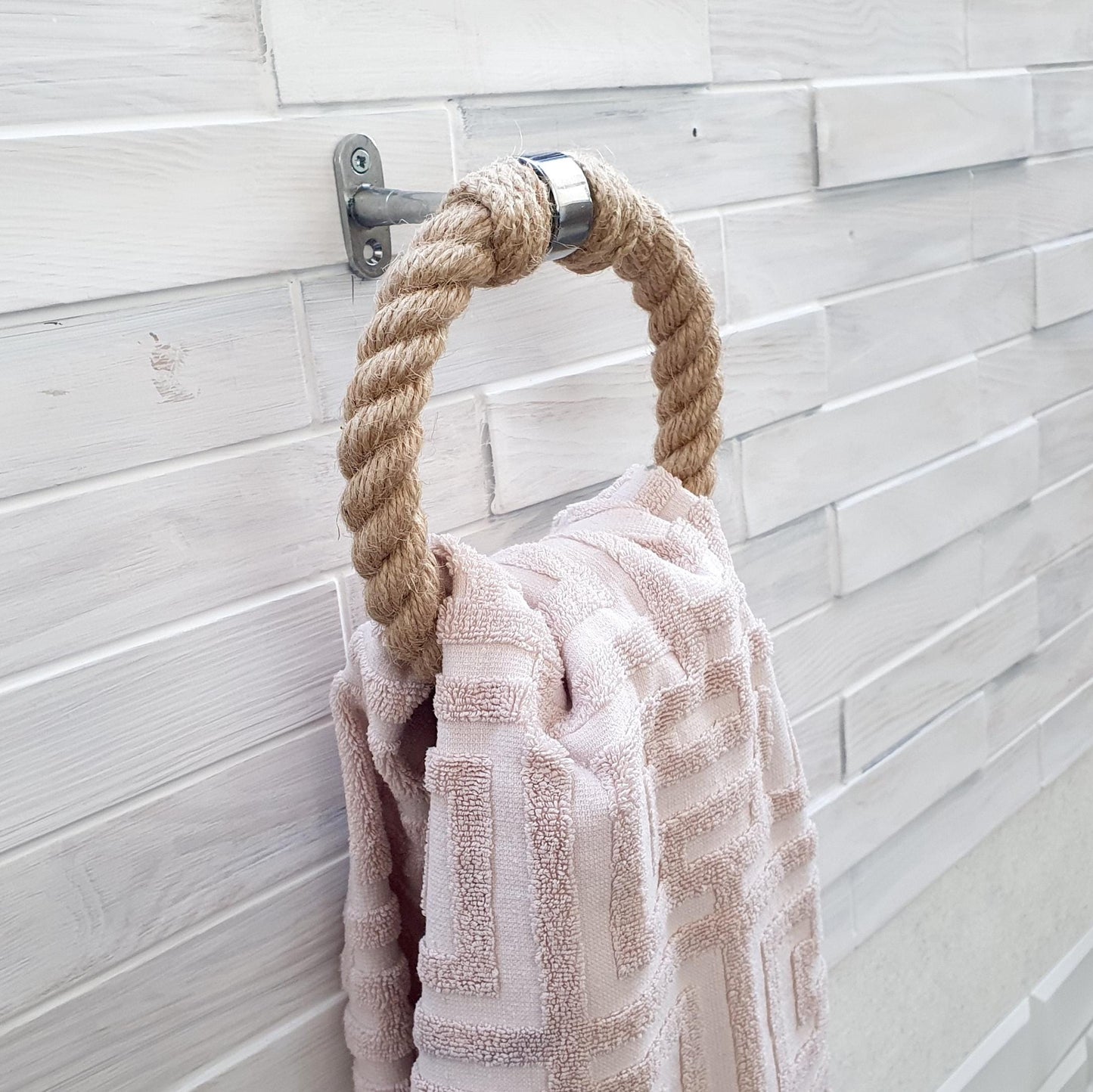 Towel hanging on a rope hook against a tiled wall