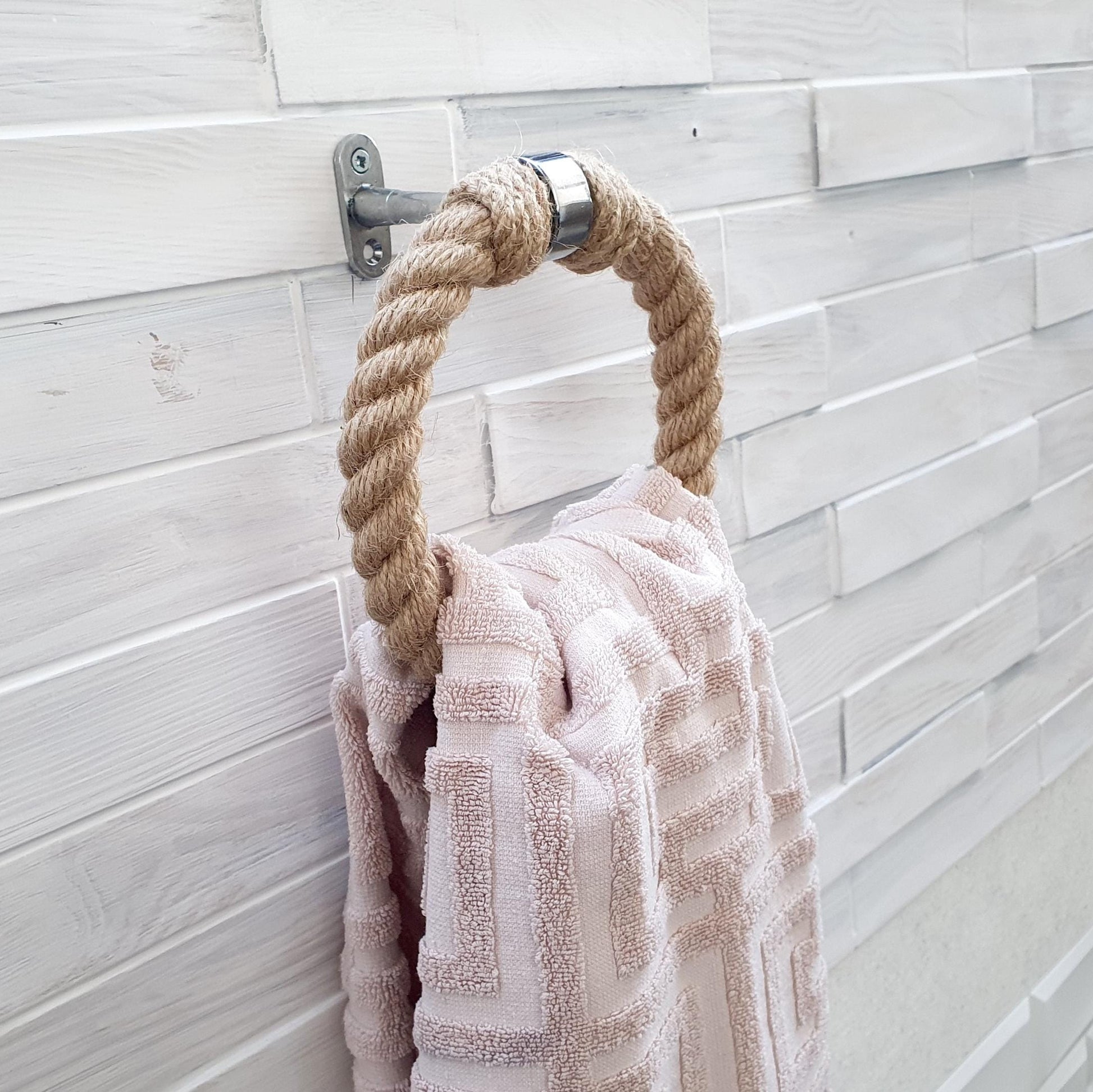 Towel hanging on a rope hook against a tiled wall